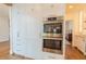 Built in microwave and oven with white cabinetry and gold hardware at 3955 Graystone Preserve Pl, Cumming, GA 30040