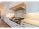 Close up of stovetop with marble backsplash, modern vent hood, and stainless steel appliances at 3955 Graystone Preserve Pl, Cumming, GA 30040