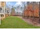 View of a green backyard with mature trees and a blue house with white trim in the background at 12867 Etris Walk, Roswell, GA 30075
