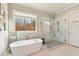 Bright bathroom featuring a modern tub, a glass-enclosed shower and a large window at 12867 Etris Walk, Roswell, GA 30075