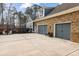 View of a spacious three-car garage, long driveway, and partial view of a brick and siding house at 12867 Etris Walk, Roswell, GA 30075