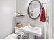 A half bathroom with a white pedestal sink and a round mirror at 237 Elmbrook Ln, Canton, GA 30114