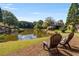 Beautiful home backyard features a serene lake view with chairs for relaxation at 5080 Riverlake Dr, Peachtree Corners, GA 30097