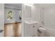 All-white bathroom featuring a vanity and shower-over-tub combination alongside a light-filled adjacent room at 5080 Riverlake Dr, Peachtree Corners, GA 30097