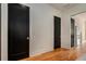 Hallway featuring hardwood floors, white walls, black doors, and stainless steel refrigerator at 165 Breakspear Ln, Fayetteville, GA 30214