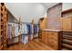 Spacious closet features wooden organizers, hanging clothes, and an exposed brick wall at 1696 N Pelham Ne Rd, Atlanta, GA 30324