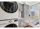 Well-lit laundry room with stacked washer and dryer and gray cabinetry with a door to the porch at 1696 N Pelham Ne Rd, Atlanta, GA 30324