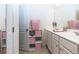 Well-lit bathroom featuring a double sink vanity with storage and pink accents at 5635 Mirror Lake Dr, Cumming, GA 30028