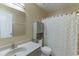 Well-lit bathroom featuring a shower with pineapple curtain, gray vanity, and a storage cabinet at 2011 Two Springs Way, Lawrenceville, GA 30043