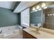 Bright bathroom featuring a soaking tub, neutral tile, and single sink vanity with a large mirror at 2011 Two Springs Way, Lawrenceville, GA 30043