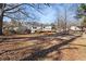 View of the backyard with trees, a wooden deck, detached garage, and leaves on the ground at 248 N Lake Dr, Jonesboro, GA 30236