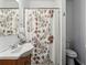 Well-lit bathroom with vanity, sink, toilet, and shower featuring a floral-patterned curtain at 569 Alexander Farms Sw Vw, Marietta, GA 30064