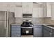 Galley kitchen features white upper cabinets, gray lowers, stainless appliances, and granite counters at 130 Valley Rd, Stockbridge, GA 30281