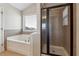 Bathroom with a tub, tiled surround, window, glass door shower and tile floors at 6525 Oak Highlands Ct, Cumming, GA 30041