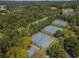 Aerial view of multiple tennis courts surrounded by lush greenery and a serene lake at 6525 Oak Highlands Ct, Cumming, GA 30041