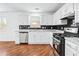 Modern kitchen featuring white cabinets, dark backsplash, stainless steel appliances, and hardwood floors at 6800 Bells Landing Way, Rex, GA 30273