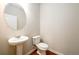 This powder room features a pedestal sink, round mirror, and wood-look flooring at 103 Magnaview Dr, Mcdonough, GA 30253