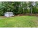 This grassy backyard features mature trees, a shed and plenty of room to play at 152 Country Cottage Cir, Carrollton, GA 30116