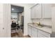 View of a butler's pantry with granite counters, gray cabinets, and dark wood flooring at 5417 Flat Rock Pt, Stonecrest, GA 30038