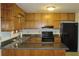 Functional kitchen with wooden cabinets, black appliances, and countertop space for meal preparation at 661 White Bird Way, Fairburn, GA 30213