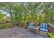 Back deck surrounded by trees and featuring two chairs and a small table at 308 Lismore Ter, Woodstock, GA 30189