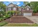Charming two-story brick home features a well-manicured front yard, a two-car garage, and mature landscaping at 308 Lismore Ter, Woodstock, GA 30189