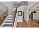 A stunning foyer features a staircase with iron spindles, hardwood floors, and a view into the kitchen at 308 Lismore Ter, Woodstock, GA 30189
