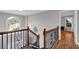Hallway with hardwood floors, decorative iron railing, and a large arched window at the landing at 308 Lismore Ter, Woodstock, GA 30189