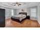 A cozy main bedroom boasts a tray ceiling, hardwood floors, and large windows with plantation shutters at 308 Lismore Ter, Woodstock, GA 30189