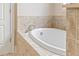 Close up of an oval tub with tan tile and silver faucet at 2300 Peachford Rd # 4004, Atlanta, GA 30338