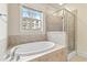 Bright bathroom showcasing an oval tub with tan tile and a glass shower door at 2300 Peachford Rd # 4004, Atlanta, GA 30338