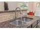 A close-up of a kitchen sink with granite countertops and a brick backsplash at 2300 Peachford Rd # 4004, Atlanta, GA 30338