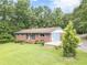 Charming brick home with a cozy front porch and blue shutters, surrounded by lush greenery and mature trees at 5255 Post Rd, Winston, GA 30187