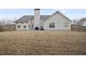 View of backyard featuring dormant grass, house and wooden fence at 129 Windy Cir, Mcdonough, GA 30253