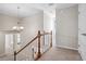 Well-lit hallway with carpet, chandelier, white trim, and wooden banister that complements the neutral decor at 4411 Windsor Oaks Cir, Marietta, GA 30066