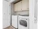 Well-lit laundry room featuring white washer and dryer units and convenient overhead storage cabinets at 4411 Windsor Oaks Cir, Marietta, GA 30066