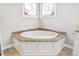 Corner soaking tub with granite surround, tile floors, and decorative windows at 4411 Windsor Oaks Cir, Marietta, GA 30066
