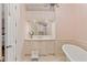 Inviting bathroom featuring a soaking tub, cream walls and cabinets, and a wall mirror at 3977 Sweet Bottom Dr, Duluth, GA 30096