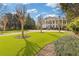 Expansive lawn highlights the columned estate in the distance, framed by mature trees and meticulously manicured shrubbery at 3977 Sweet Bottom Dr, Duluth, GA 30096