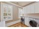 Bright laundry room with hardwood floors, white cabinetry, quartz countertops, and modern appliances at 3977 Sweet Bottom Dr, Duluth, GA 30096