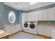 Well-appointed laundry room with built-in cabinets, a large sink, and modern washer/dryer units at 3977 Sweet Bottom Dr, Duluth, GA 30096