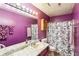 Bathroom with decorative purple walls, a marble counter, and patterned shower curtain at 60 Mountain View Cir, Covington, GA 30016