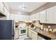 Practical kitchen layout with white appliances, ample cabinetry, and easy-to-clean tile flooring at 60 Mountain View Cir, Covington, GA 30016