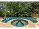 A serene in-ground pool features a hot tub and mature trees surrounding the area at 165 Ansley Way, Roswell, GA 30075