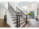 Elegant staircase with wrought iron railings, hardwood steps, and a view of the entry foyer at 165 Ansley Way, Roswell, GA 30075