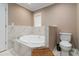 Bathroom with whirlpool tub with tile surround and window for natural light, with toilet and door on either side at 3186 Quail Ct, Decatur, GA 30034