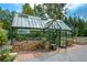 Exterior view of a lovely greenhouse featuring glass walls, brick base, and adjacent garden beds at 624 Hemlock Trl, Canton, GA 30114