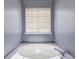 Clean, bright bathroom featuring a built-in white bathtub with chrome faucet and window with blinds at 509 Chestnut Oak Dr, Palmetto, GA 30268