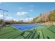 Outdoor tennis courts featuring blue and green surfaces with lighting and mature trees in background at 120 Pine Mist Cir, Alpharetta, GA 30022