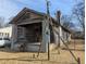 An exterior shot of a distressed single-story home with a front porch and a yard at 3072 Semmes St, East Point, GA 30344